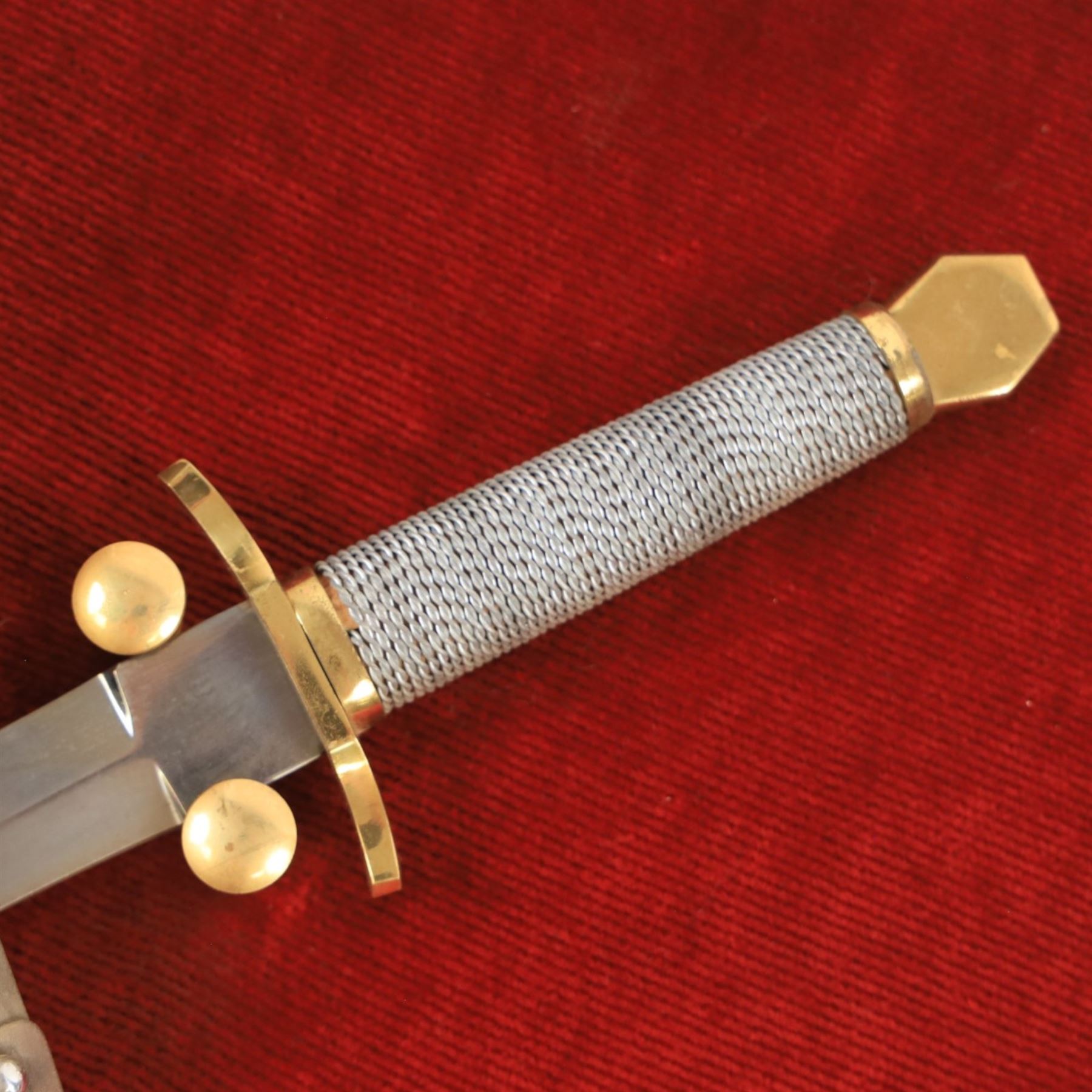 Three replica gauntlets, each housed upon a red wall shield, two with daggers, the third with a sword, largest H102cm
