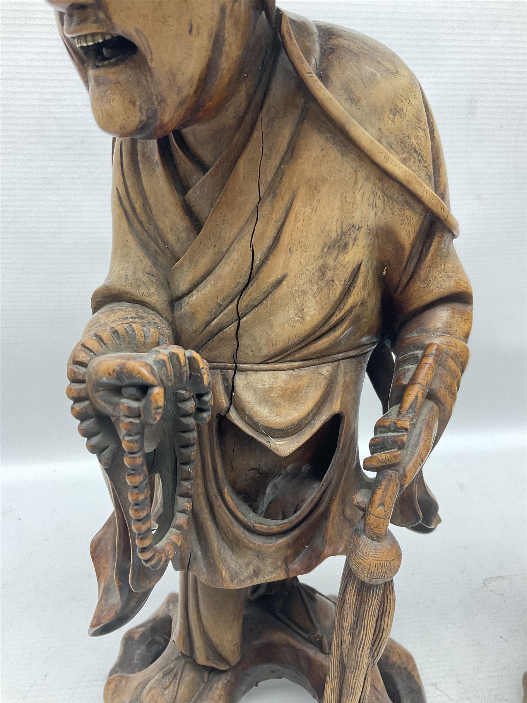 Pair of Japanese carved wooden figures, modelled as merchants in traditional dress, upon pierced naturalistic bases, tallest H39cm