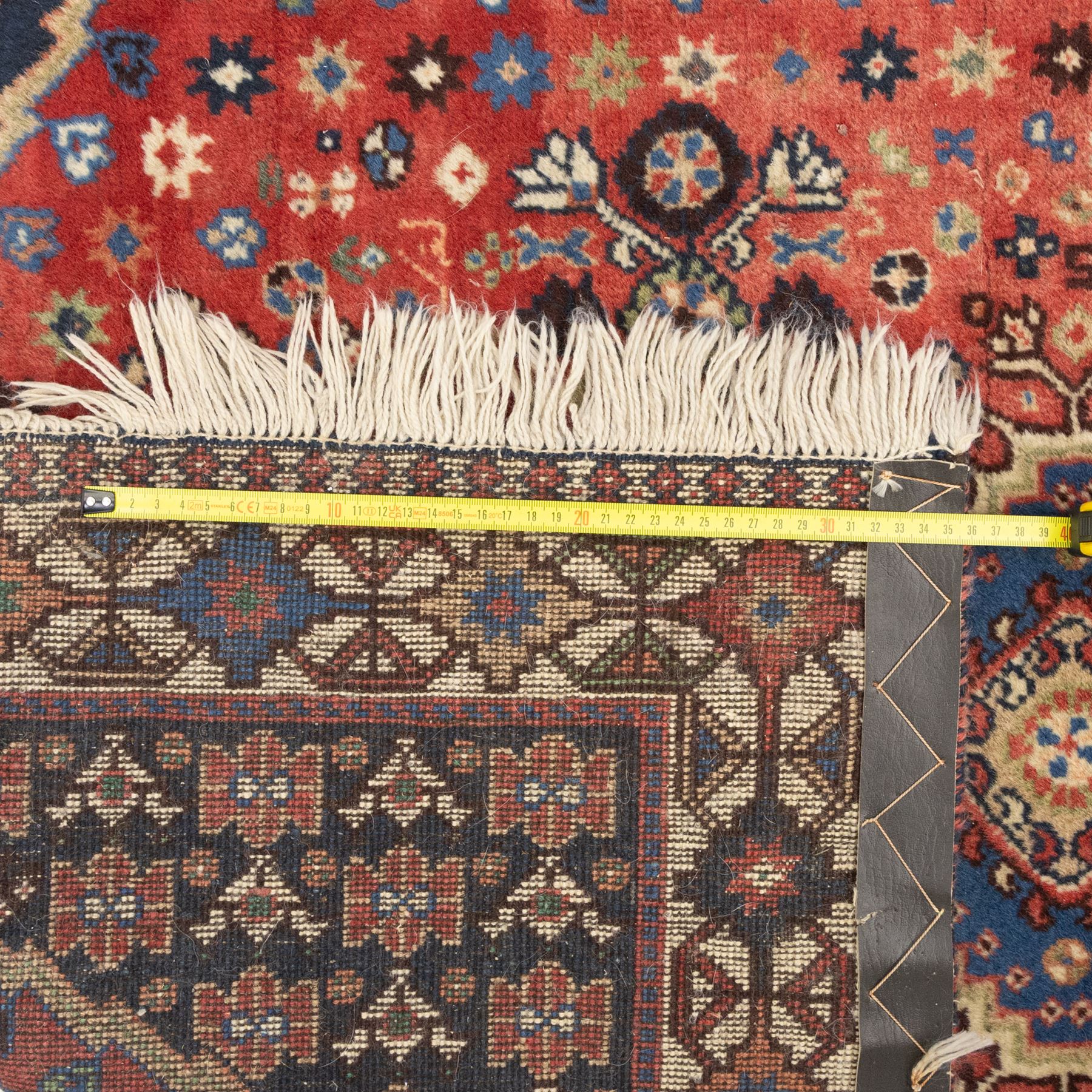 Persian Shiraz rug, wool on cotton foundation, with central row of linked diamond medallions in ivory, indigo and madder tones, stylised rosettes and angular vine motifs throughout, framed by a geometric border