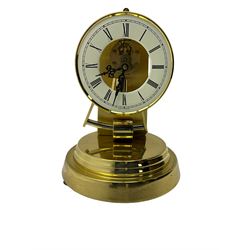  A late 20th century -  German Kieninger & Obergfell, “Kundo” battery operated
mantle clock under an acrylic shade, with an electrically operated solenoid pendulum housed on a circular brass base, skeleton movement with visible motion work through a painted 4-1/2” open chapter ring, with pierced steel hands, Roman numerals and minute track.