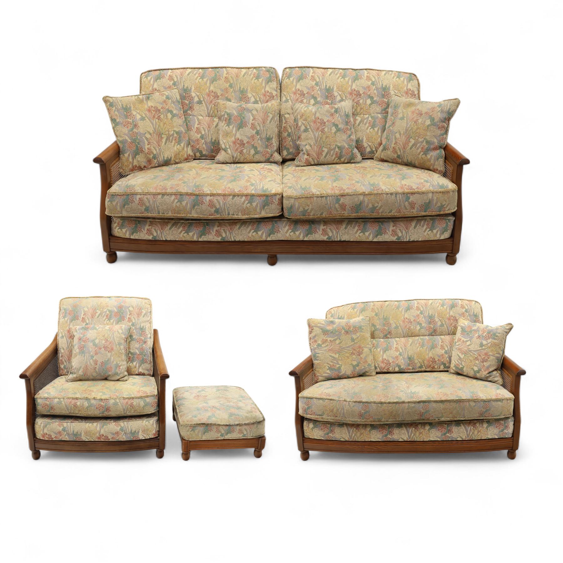 Ercol – bergère four piece suite, including armchair, two seat sofa, three seat sofa and footstool, all with removable floral upholstered cushions, the frames with side caning and rounded arm supports in stained beech

Three seat (H 87cm, D 89cm, W 196cm)
Two seat (H 87cm, D 89cm, W 137cm)
Armchair (H 87cm, D 89cm, W 87cm)
Footstool (H 28cm, D 55cm, W 55cm)