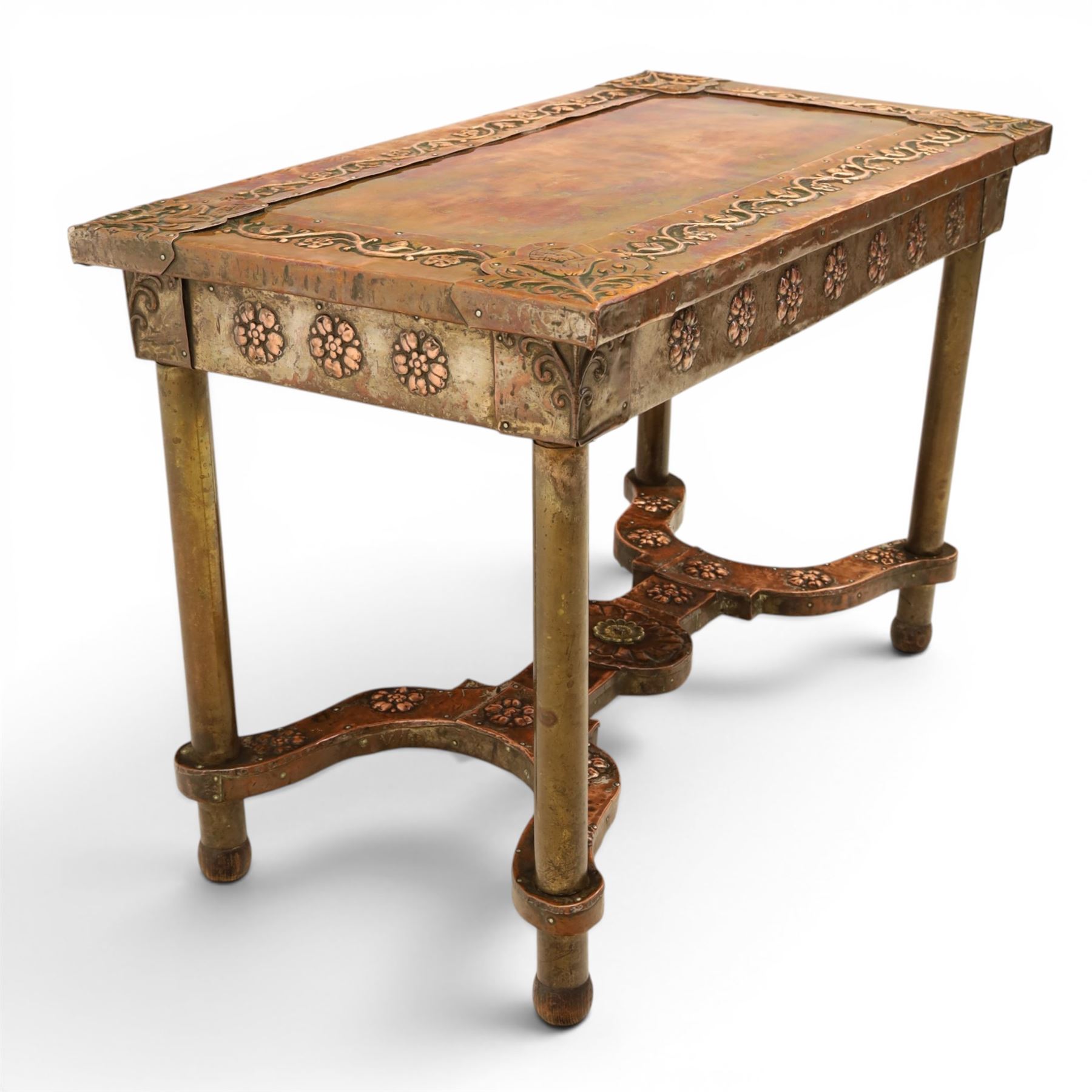 Arts and Crafts copper mounted coffee table, rectangular top with embossed foliate border and stylised corner motifs, studwork detail, on cylindrical supports united by pierced shaped stretcher with applied flowerhead bosses