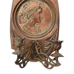 Pair of late 19th/early 20th century Art Nouveau copper twin branch wall sconces, each with shaped back plate chased with a central panel of a maiden in profile above and surmounted by foliate motifs, supporting two foliate open cast branches with bud sockets above conforming drip pans, H31cm W16cm D8.5cm
