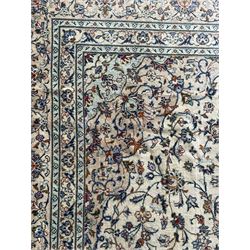 Persian Kashan ivory ground carpet, the field decorated with interlacing foliate branches and stylised plant motifs, scrolling border decorated with repeating palmettes, within floral pattern guard bands