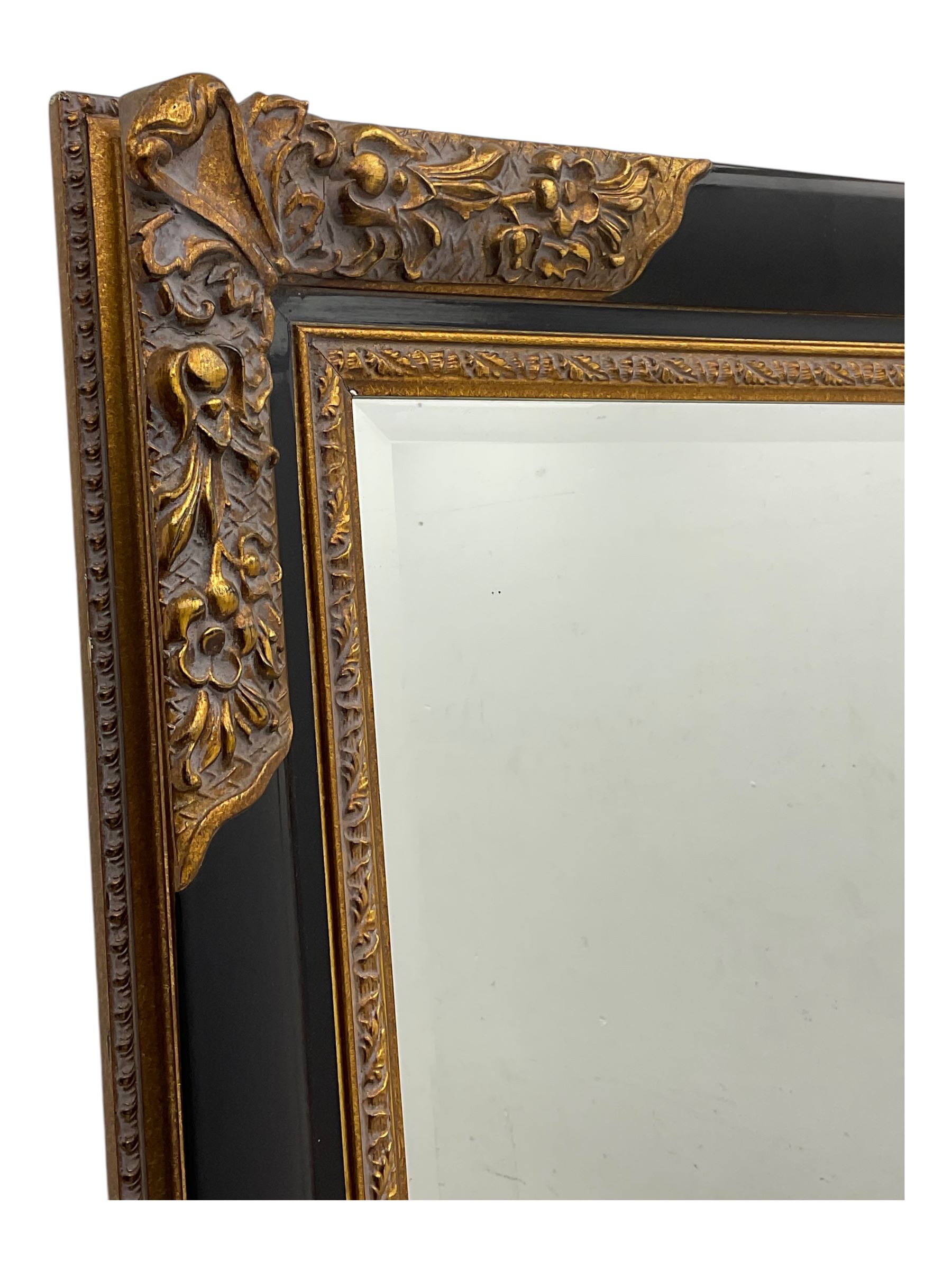 Early 20th century wall-hanging mirror, rectangular bevelled mirror plate within ebonised frame, gilt mounts to the corners carved with floral motifs 