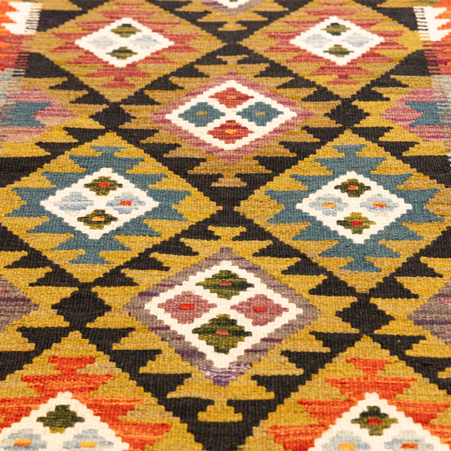 Afghan Maimana flatweave kilim runner, central field features large bold nested diamond motifs and stylized geometric lozenge patterns on olive purple, blue, and green tone ground, border stripe in orange ground, and fringe