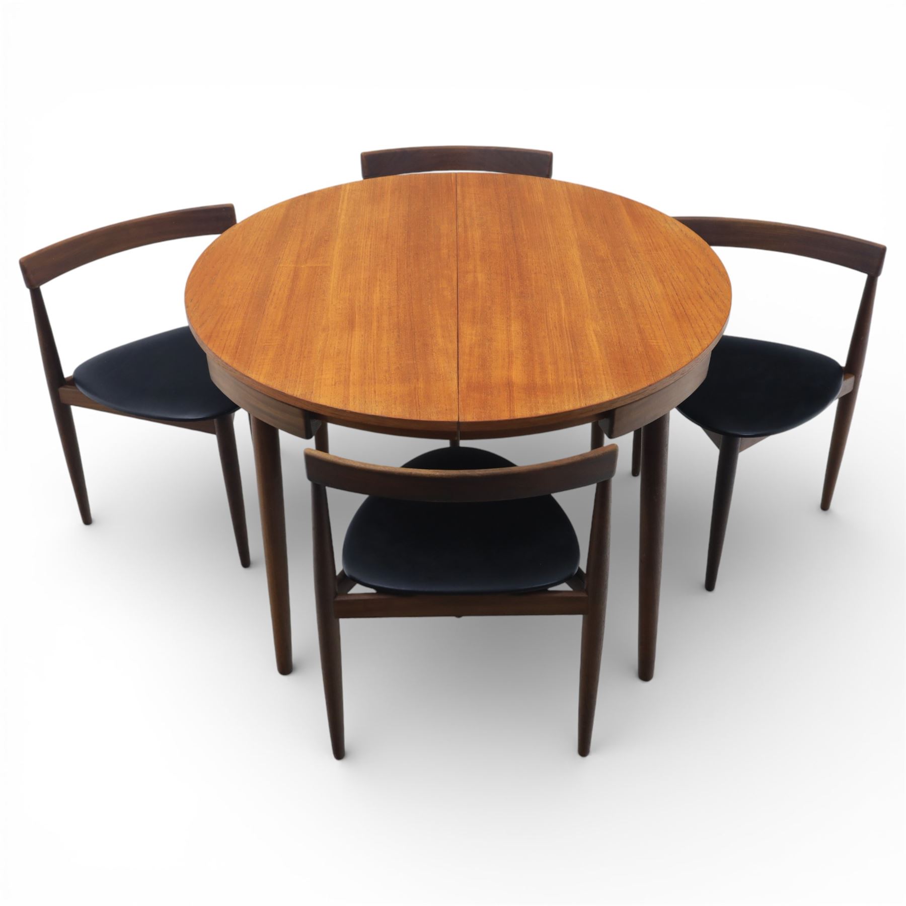 Frem Røjle - Danish teak 'Roundette' extendable dining table, circular top with softly chamfered edge and internal stowable leaf extends to 156cm, raised on four tapered cylindrical legs, accompanied by four matching dining chairs with shaped teak frames and black vinyl upholstered seats, the chairs designed to nest beneath the table when not in use