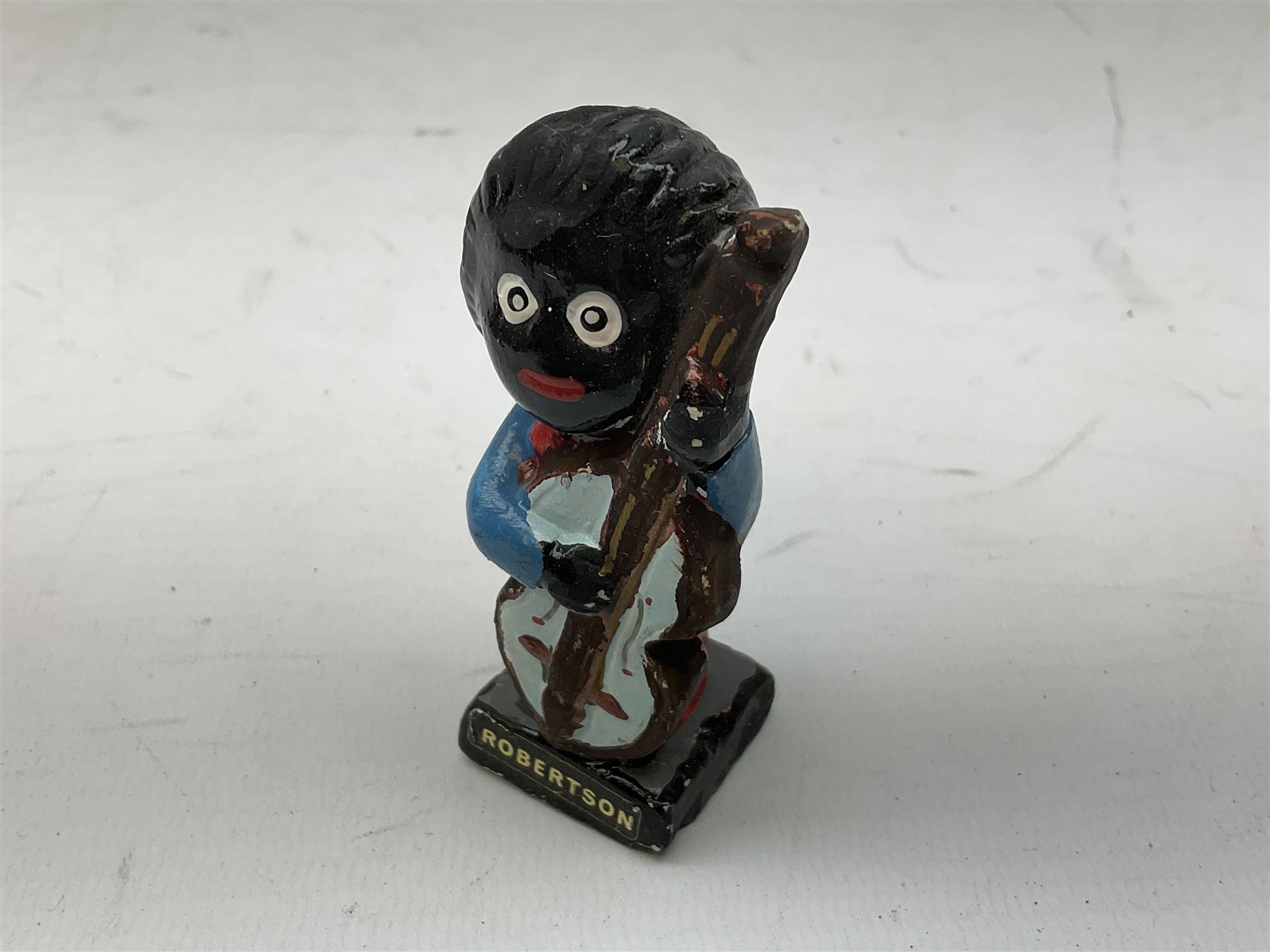 Robinson Jam plaster Golly band, including drummer and singer, H7.5cm

Originally handmade by mothers in Africa for their children from old fabric and cloth, the golly doll was adopted as the mascot and trademark for the Robertson's confectionery brand around 1910 after the company's founder John Robertson visited the US and noticed children playing with them. Robertson's Gollies have been collected by people across the UK and around the world for generations but garnered a contentious image in the 1980s because of links to racism. The trademark was removed from Robertson's branding in 2001.