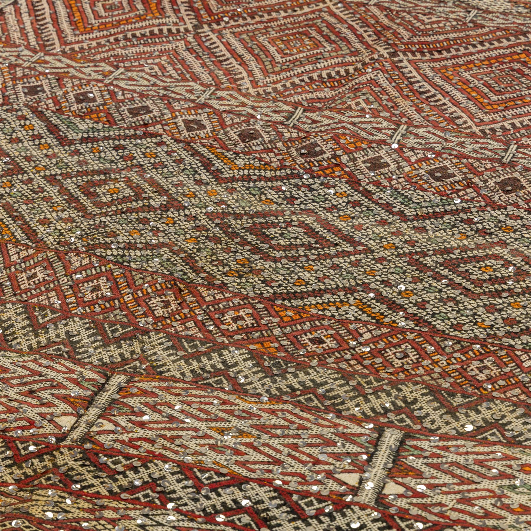 Moroccan Berber kilim rug, flatwoven with bands of geometric lozenge and chevron motifs in red, orange, ivory and green, decorated with applied sequins, fringed ends