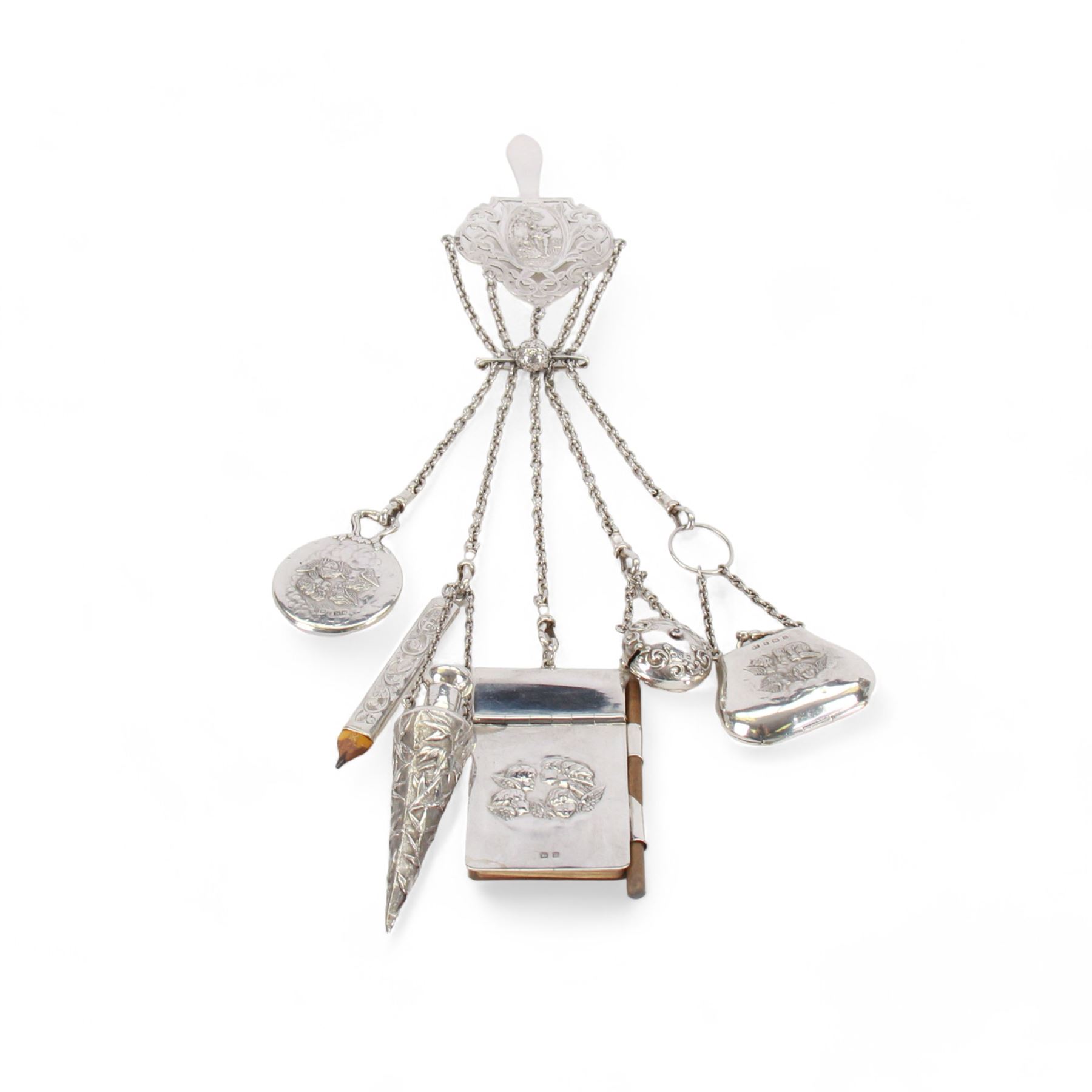 Victorian and later silver chatelaine, the shaped and foliate pierced clasp with embossed oval panel of a courting couple, hallmarked Levi & Salaman, Birmingham 1899, supporting six accessories on five chains: a circular mirror embossed with putti, hallmarked Henry Matthews, Birmingham 1911, pencil holder engraved with foliate scrolls, hallmarked Francis Webb, Birmingham 1914, conical scent bottle decorated with bamboo, (unmarked but testing as silver), aide memoire embossed with putti, hallmarked Samuel M Levi, Birmingham 1911, tape measure of compressed spherical form, hallmarked Henry Matthews, Birmingham 1899, and a purse with embossed putti, hallmarked Birmingham 1909, makers mark worn and indistinct, at longest point L31cm

