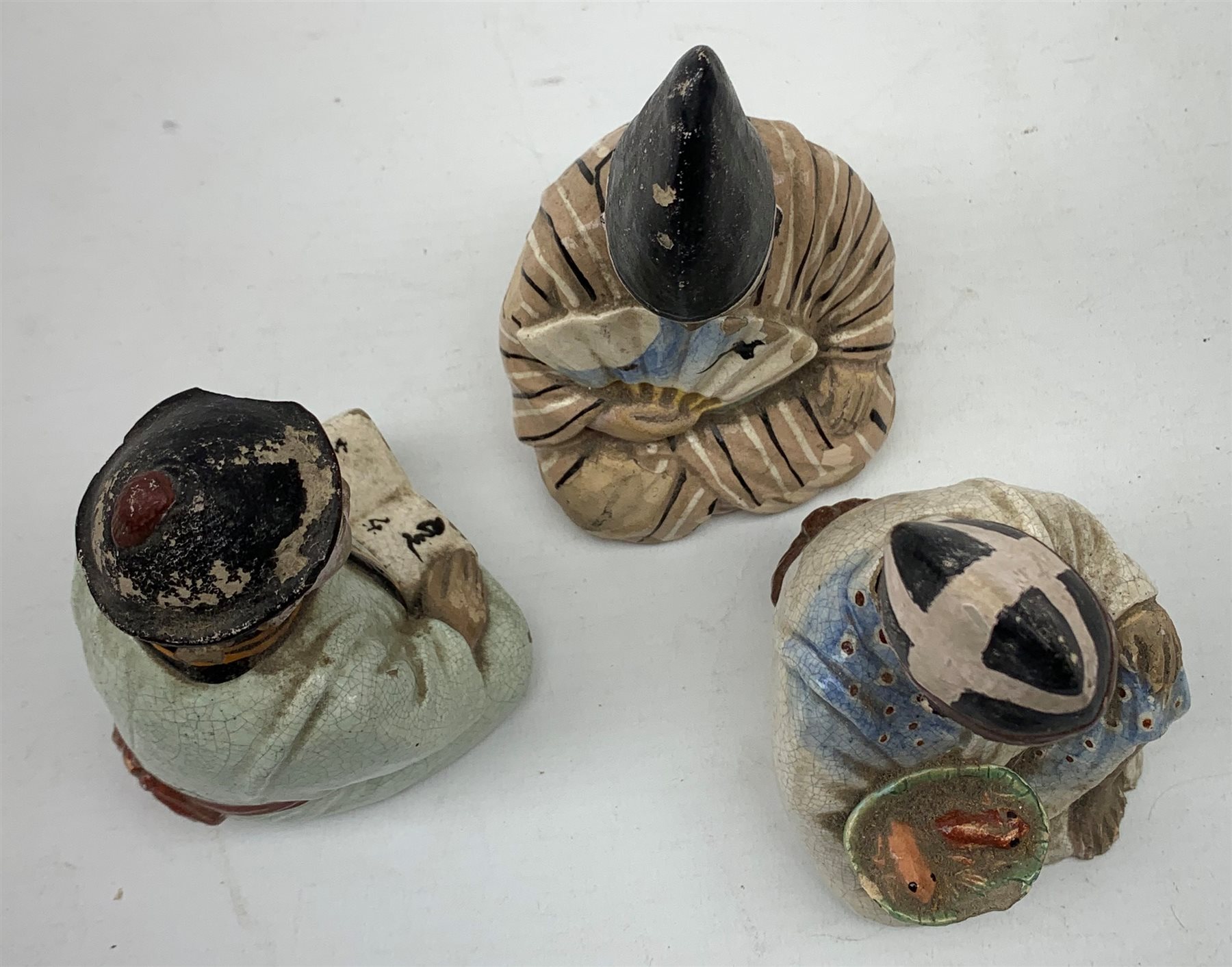 Three Japanese earthenware nodding head figures, each modelled as a seated male, tallest H13.5cm.  