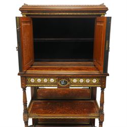 Fine late 19th century Aesthetic Movement ebony and amboyna cabinet on stand with parcel-gilt detail, the moulded cornice with pierced gilt-brass three-quarter gallery above a pair of panelled doors centred by oval porcelain portrait plaques within gilt-metal ribbon-tied frames, the doors further enriched with gilt-metal foliate mounts and flanked by classical figural terms, enclosing a shelved interior, the projecting lower section with amboyna top above a frieze drawer set with a series of floral porcelain roundels within pierced gilt-metal mounts and a central oval floral plaque, raised on turned and fluted supports with gilt-heightened detail, the mirrored back behind two amboyna shelves with pierced gilt-brass galleries, on turned feet
