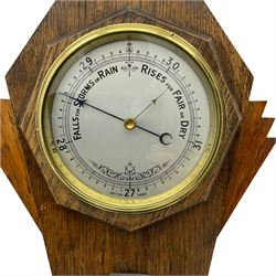 A mid-20th century British made aneroid barometer housed in an inverted oak case in the art deco style,  with a six-inch silver effect dial recording air pressure from 27 to 31.9 inches with weather predictions, steel indicator hand and brass recording hand within a spun bezel and flat bevelled glass, spirit thermometer recording the temperature in degrees Celsius and Fahrenheit. 



