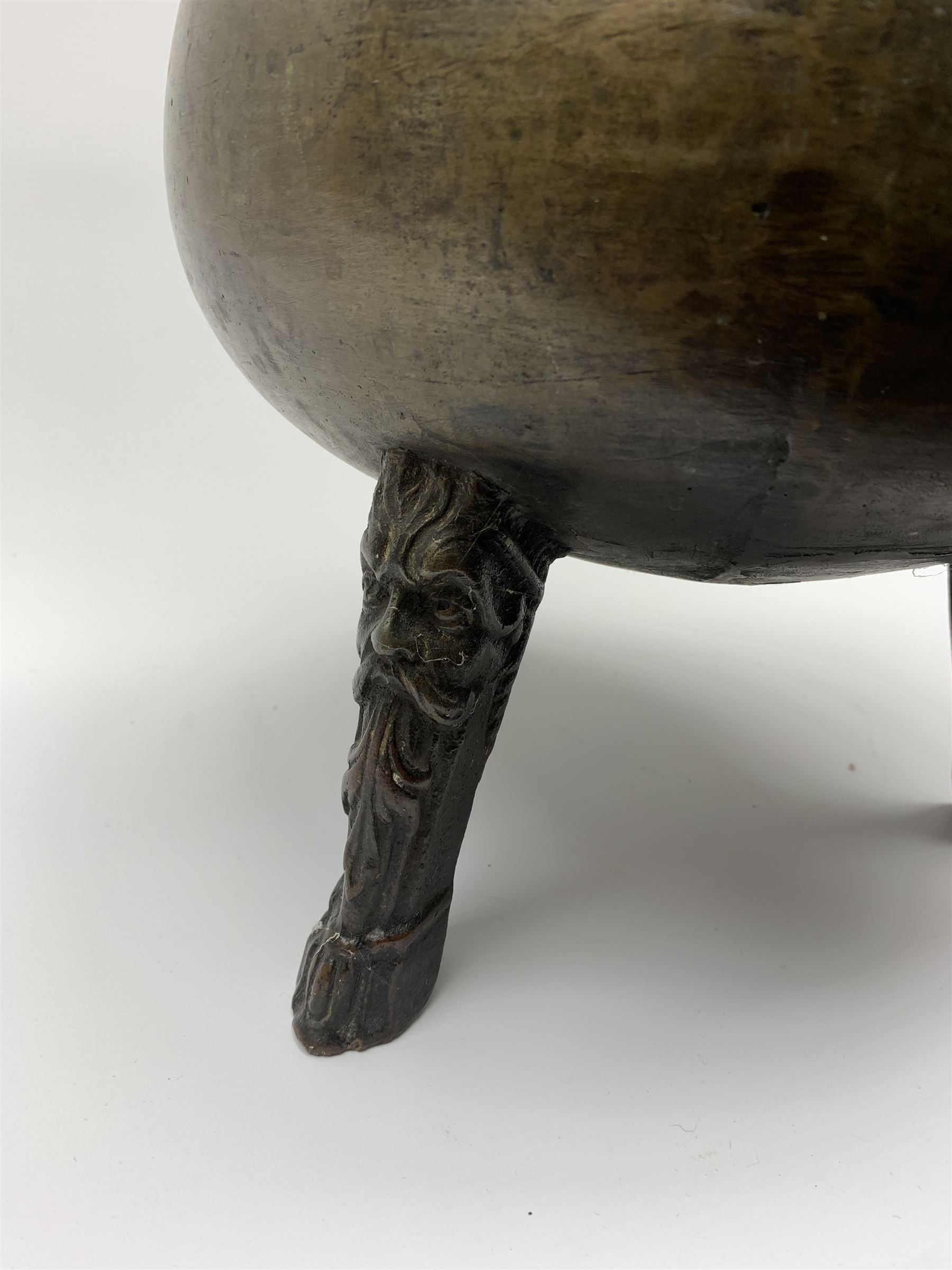 17th century bronze cauldron, probably German or Austrian, of bellied form with twin angular handles supporting a twisted handle, upon three splayed zoomorphic bearded mask feet, not including handle H30cm, rim D22cm