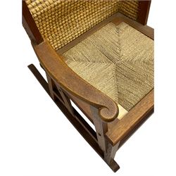 Reynold Eunson (1932–1978) for David Munro Kirkness, Kirkwall, Orkney - oak framed Orkney rocking chair, woven straw curved back, drop-in rush seat, the arm terminals with carved end scroll, on square tapering supports joined by plain stretchers, the front rail inscribed with makers marks