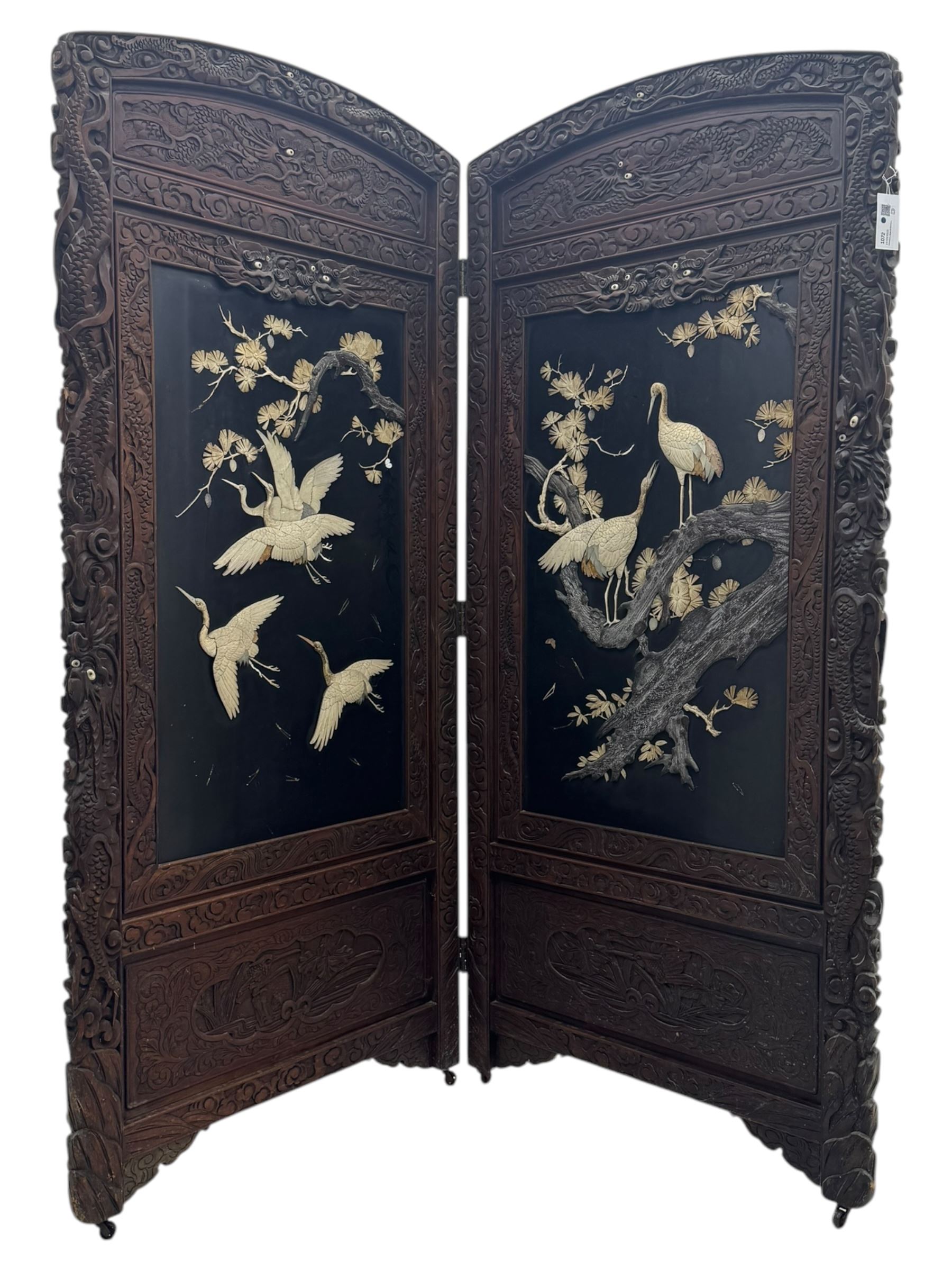 Meiji period (1868–1912), Shibayama lacquer carved hardwood two-fold screen inlaid with mother-of-pearl, bone, and ivory, decorated on one side in high relief and inlaid in a  Shibayama manner with oriental storks flying below flowering branches,  the reverse lacquer panels depicting flowering cherry trees. This item has been registered for sale under section 10 of the APHA Ivory Act.