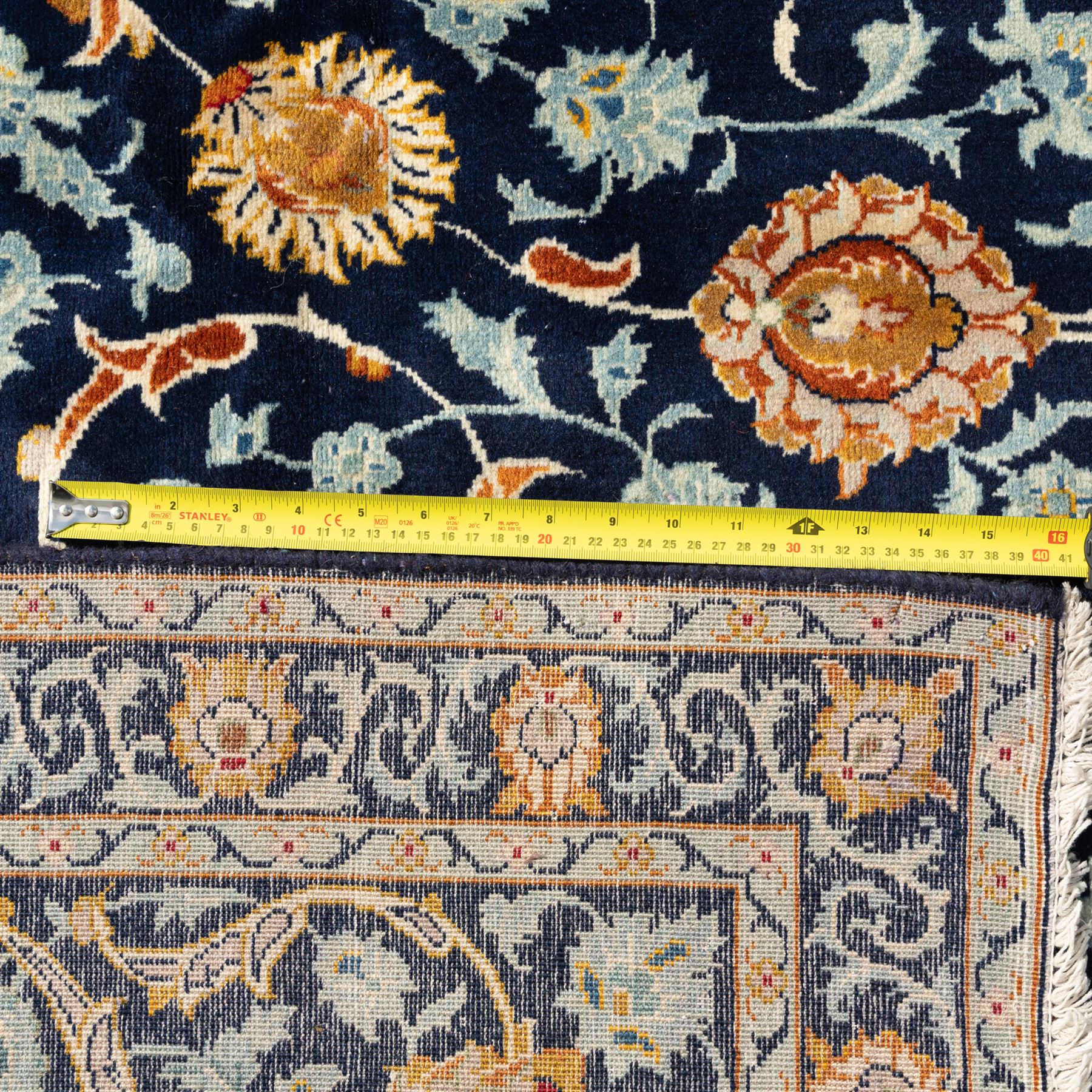 Persian Kashan carpet, navy field with an all-over design of scrolling vines, palmettes and rosettes in gold and pale blue, enclosed by multiple floral borders with stylised palmette motifs, originating from Central Iran