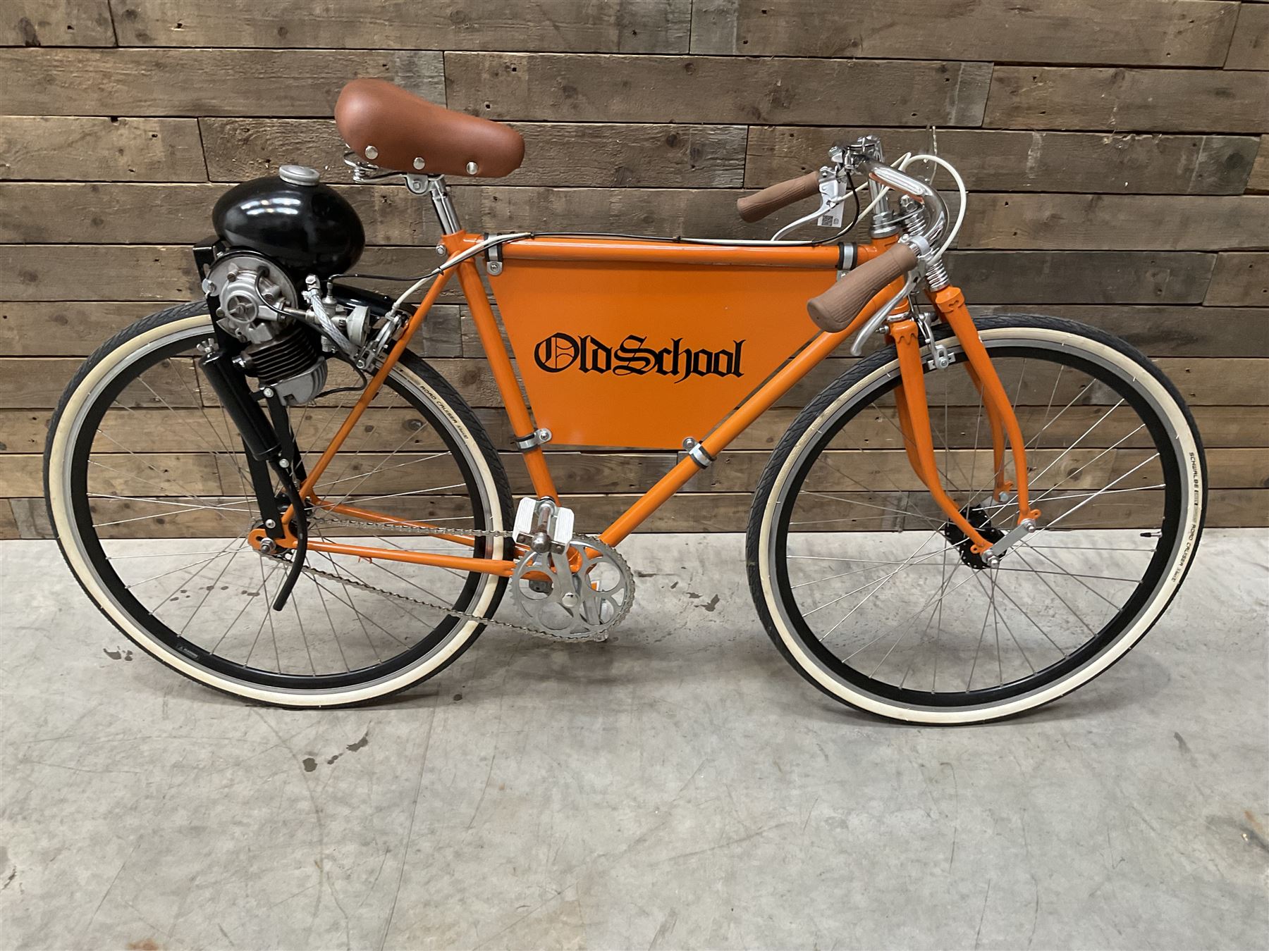 Fully restored vintage advertising bicycle with 2 stroke petrol engine, orange frame, tan leather seat