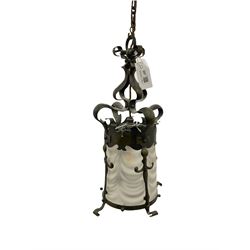 Early 20th century Arts & Crafts patinated brass hall lantern, the shaped mount housing an opaque waved glass shade, H46cm