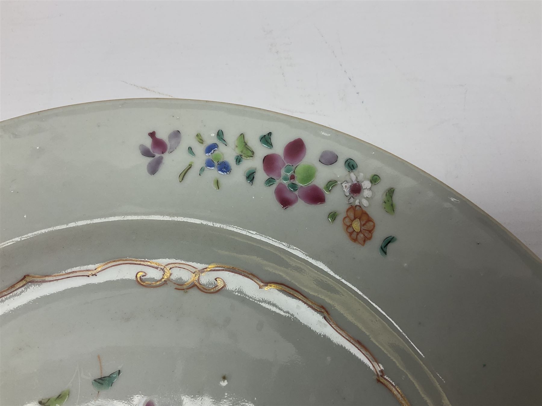 Three 18th century Chinese Famille Rose plates, the first example enamelled with blossoming peonies, rockwork and fence, the other two examples of similar design, decorated with blossoming peonies and sprigs within shaped inner borders, each approximately D23cm