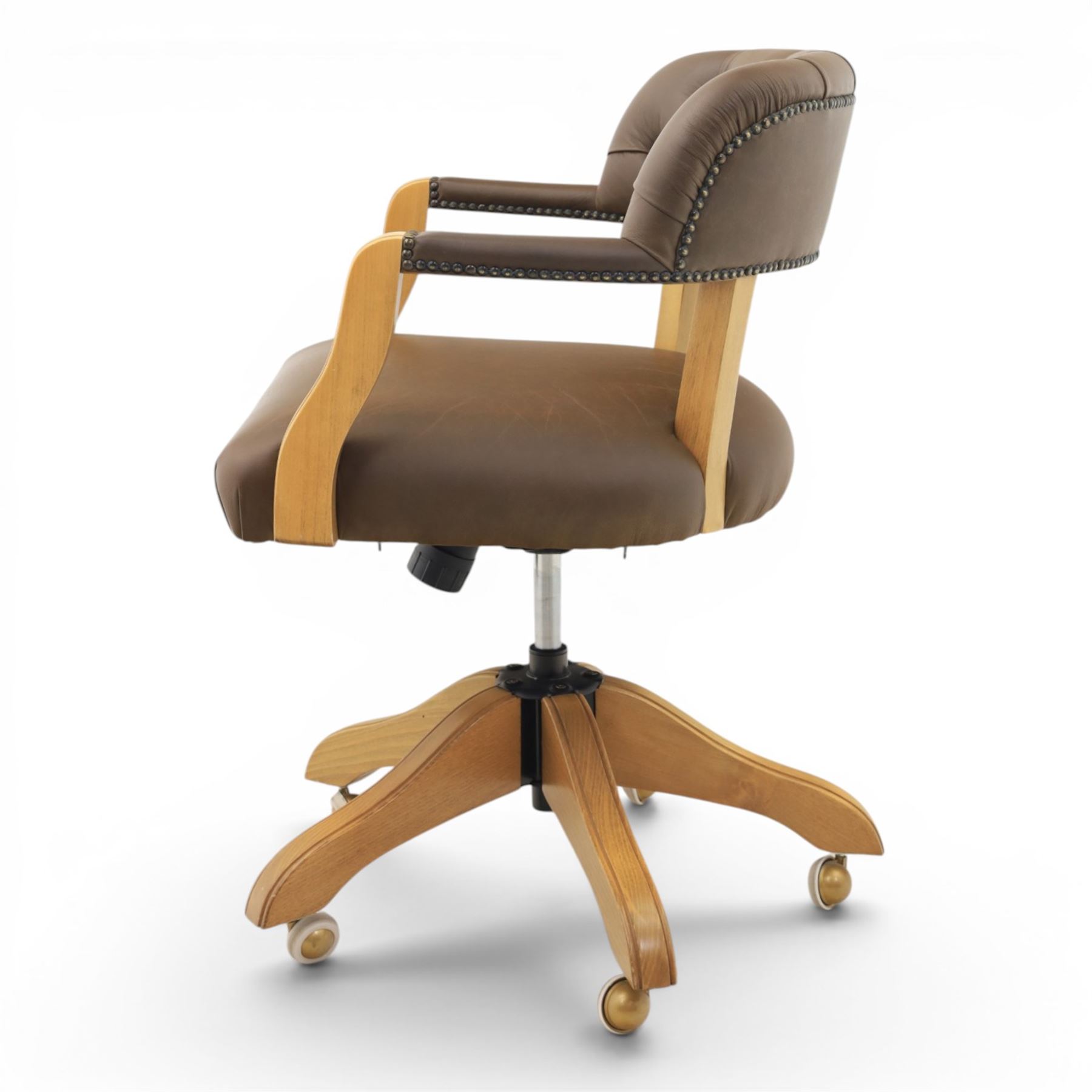 Captain's swivel desk chair upholstered in buttoned tan leather, button backed chair rail, padded and downswept arms, raised on a six point base with castors