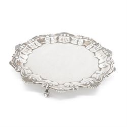Edwardian silver waiter, of typical form with palmette and C scroll rim, upon three scroll...