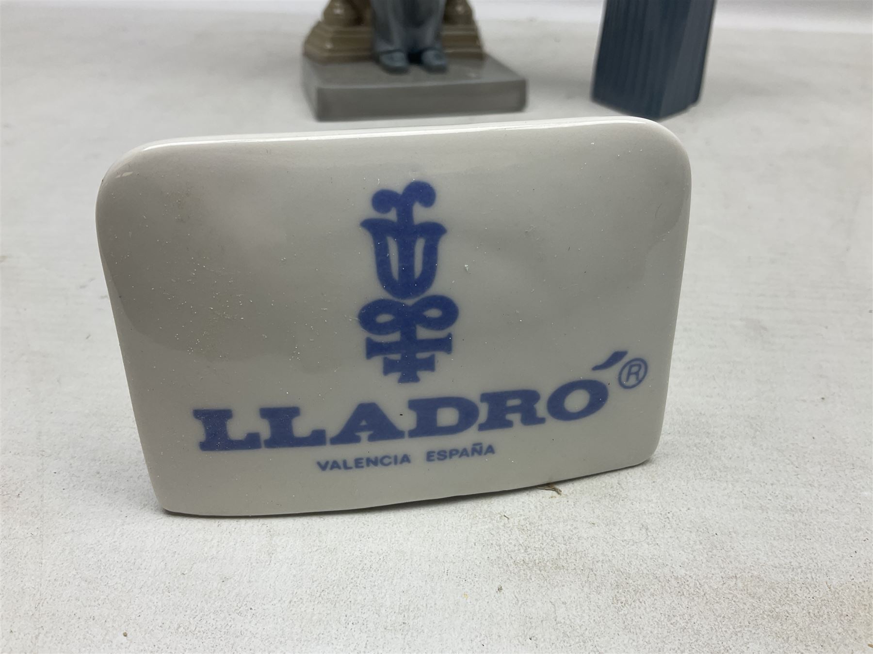 Two Lladro figures, comprising Conductor no 5196 and Prayerful Moment no 5500 together with a Lladro plaque and two Lladro candle holders, Dolphins at Play no 17666 and Sailing the Seas no 17665, all with original boxes, largest example H33cm 