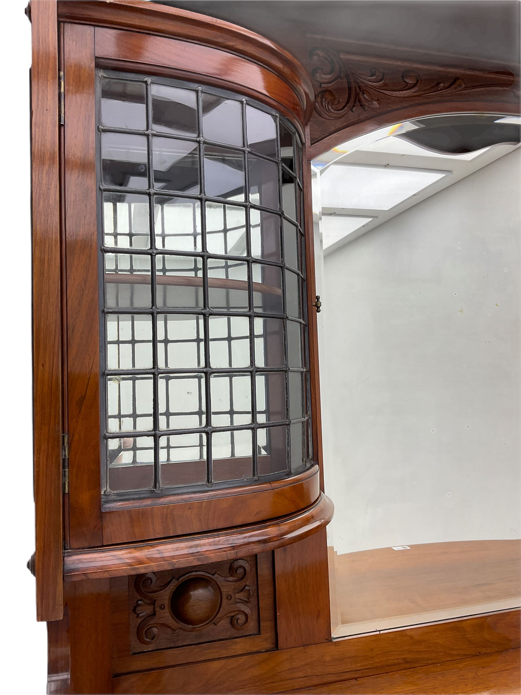 Late Victorian walnut mirror back sideboard or dresser, the raised back fitted with two curved and lead glazed cabinets, central arched bevelled mirror, the sideboard with break bowfront, fitted with six drawers and two cupboards, the cupboard doors panelled and carved with scrolls, shell and plant motifs, shaped apron with cabriole feet
