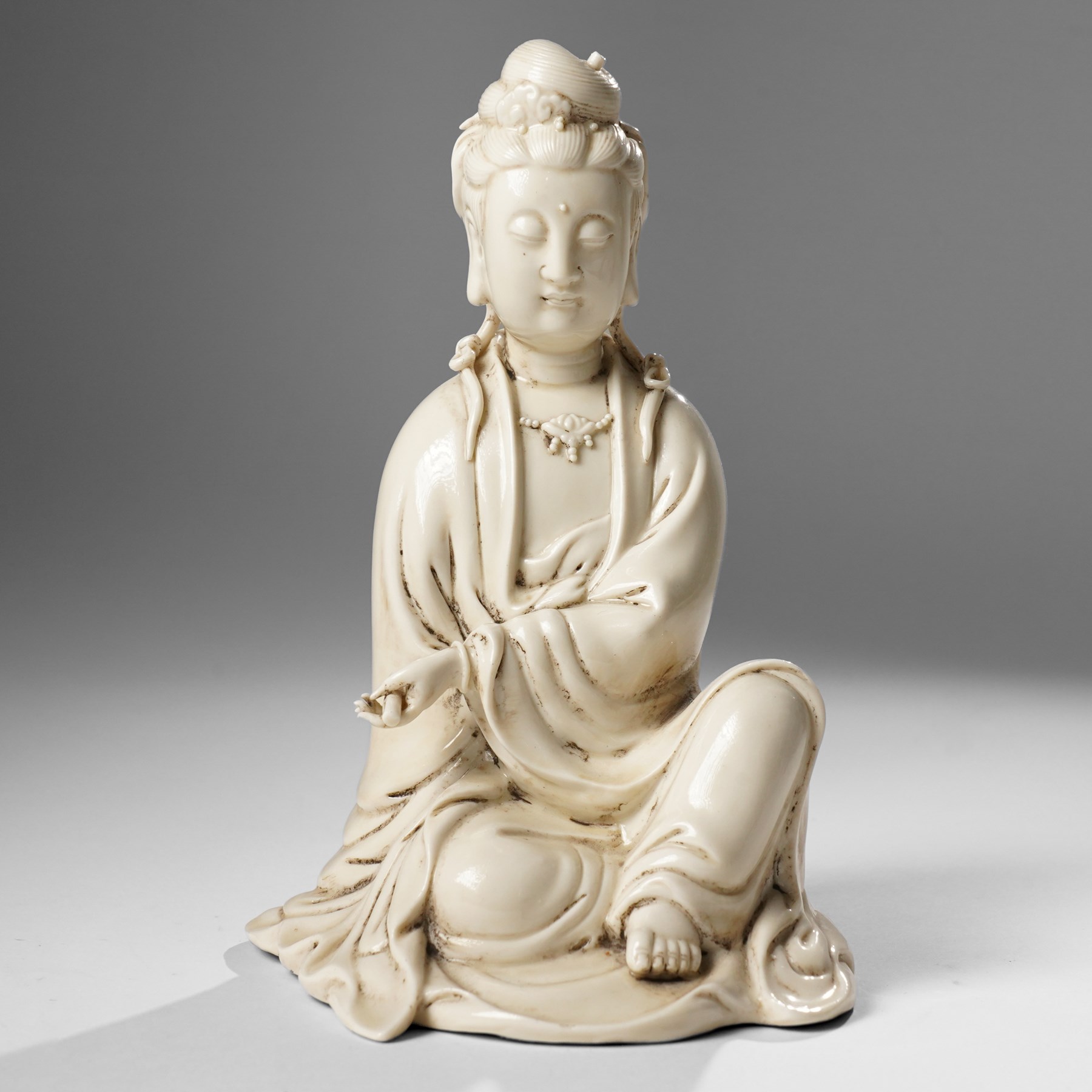 Three Chinese blanc de chine figures, each depicting Guanyin seated, Dehua province, two with double gourd and potters seal marks to the reverse 