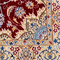 Central Persian Nain hand-knotted rug, crimson field, with central ornate ivory medallion with scrolling arabesques and flowering vine ornaments within a dense floral lattice framed by pale blue corner spandrels and enclosed with an ivory border of scrolling vine and palmette decoration between multiple guard stripes, with cotton fringe ends 