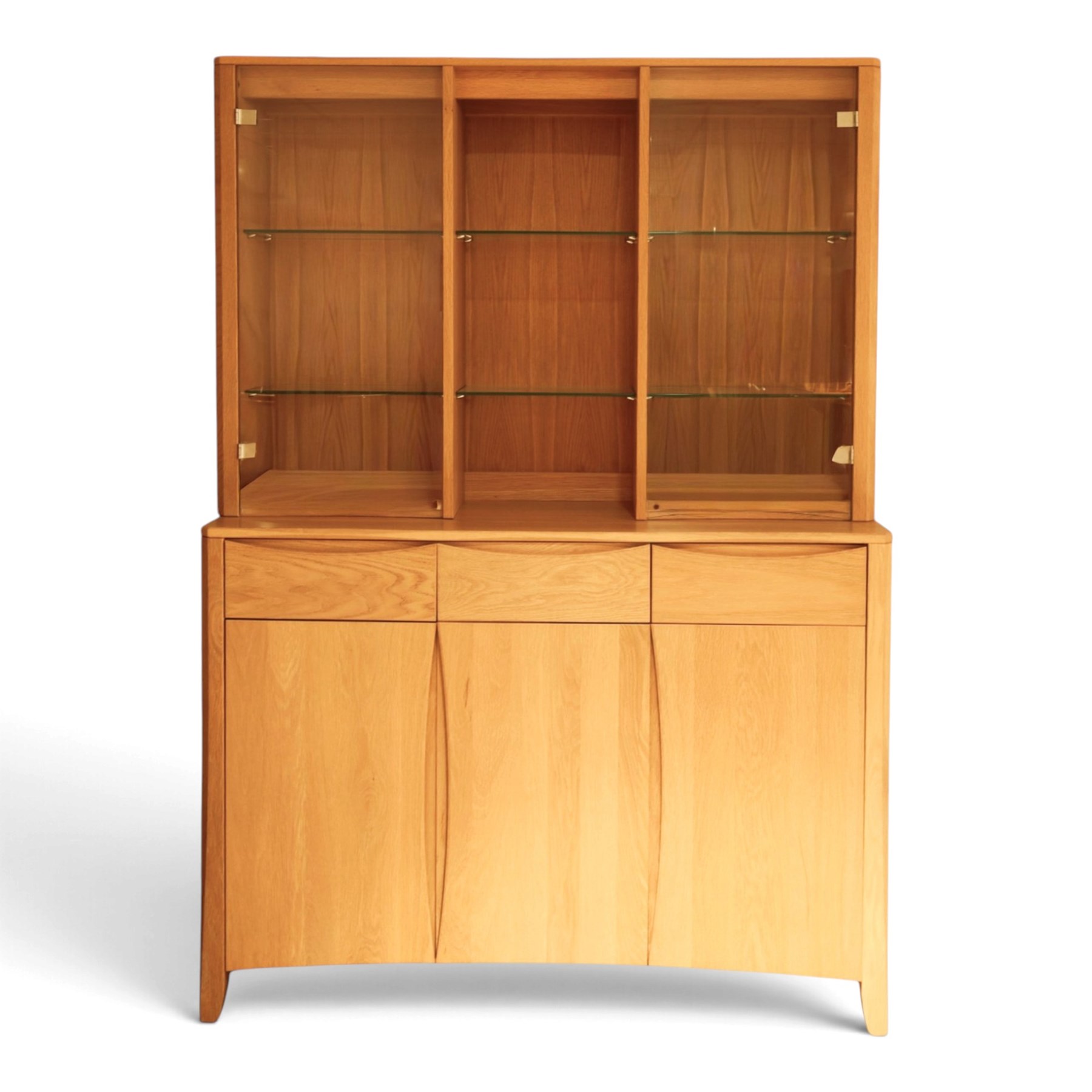 Ercol - 'Artisan' light oak dresser, upper section with cantered corners, with central open area fitted with adjustable glass shelves, flanked by twin glazed cabinets with further adjustable glass shelving, the lower section with three shorts drawers with recessed handles, above three cupboard doors with recessed handles enclosing adjustable wooden shelves, raised on short tapering supports 