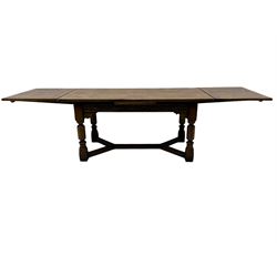 Early 20th century Jacobean design draw-leaf oak dining table, rectangular top with carved frieze depicting scrolling foliage and grape clusters, sliding extending leaves, raised on robust turned supports united by H-stretcher  