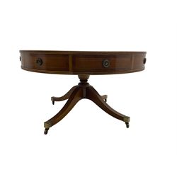 Georgian style yew wood drum table, circular top with green and tooled leather inset, fitted with four drawers, on turned pedestal base with four splayed supports, brass cups and castors