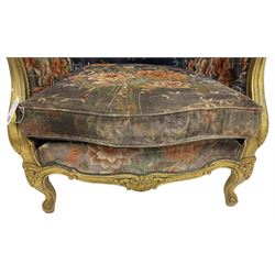 Pair of Louis XVI design gilt framed wingback armchairs, cresting rail carved and moulded with foliate decoration and C-scrolls, upholstered in buttoned floral patterned mauve velvet with loose seat cushion, scallop carved apron over cabriole supports