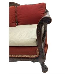 Early 20th century bergère three seat settee, shaped shell carved cresting rail, double caned back and sides, scrolled upright arms and shaped apron carved with shell and foliage, on hairy paw carved feet