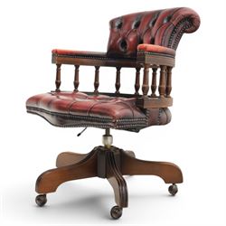 Captains swivel desk chair upholstered in oxblood leather, buttoned back and seat, shaped arm bow raised on turned spindles, five spoke base raised on castors
