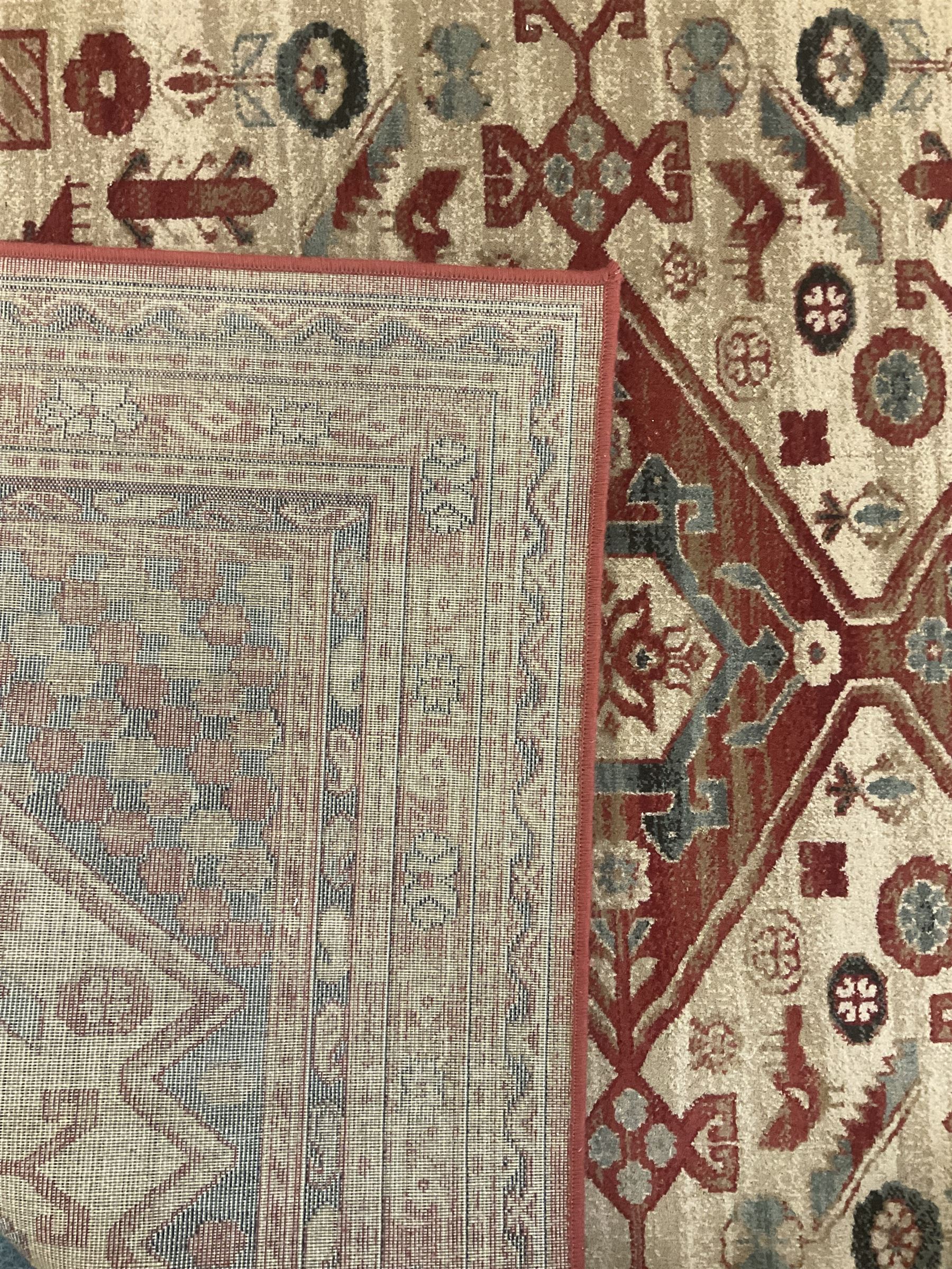 Persian design red ground rug, the field decorated with three interlinked lozenges and small stylised plant motifs, the multiple band border decorated with Boteh and floral motifs