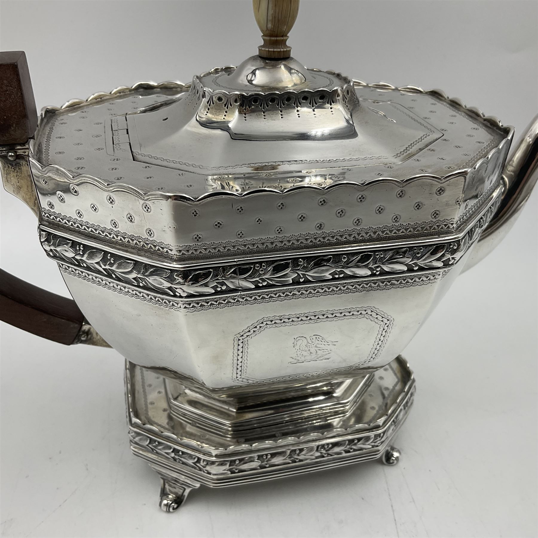 Victorian silver four piece tea service, comprising teapot, teapot stand, twin handled open sucrier and milk jug, each of octagonal form with foliate bud border and engraved decoration including crest to canted panels, and vacant panels, the teapot with ivory finial to the hinged cover and later wooden handle, hallmarked Edward Barnard & Sons Ltd, London1896, teapot including finial H15cm, milk jug including handle H16cm, teapot stand W11.5cm

This item has been registered for sale under Section 10 of the APHA Ivory Act
