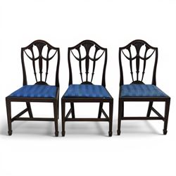 Set of eight George III style mahogany dining chairs, comprising two carvers and six singles, each with shaped top rail above pierced splay carved with feathers, with drop in stuffover seats upholstered in blue striped fabric, raised upon square tapering legs joined by stretchers, together with a mahogany twin pedestal dining table, the oval top with central leaf raised upon turned columns and splayed reeded legs terminating in lion paw feet and brass castors, 