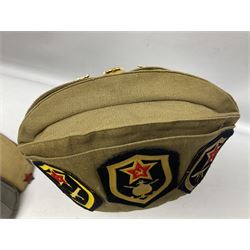 Four side caps - WW2 Russian, post-WW2 Russian and two East German; all with badges, one with multiple metal badges (4)
