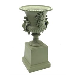 20th century green painted cast iron campana urn on plinth, gadroon moulded rim, the body with mask and scrolled cartouche mounts, on square plinth with moulded skirt