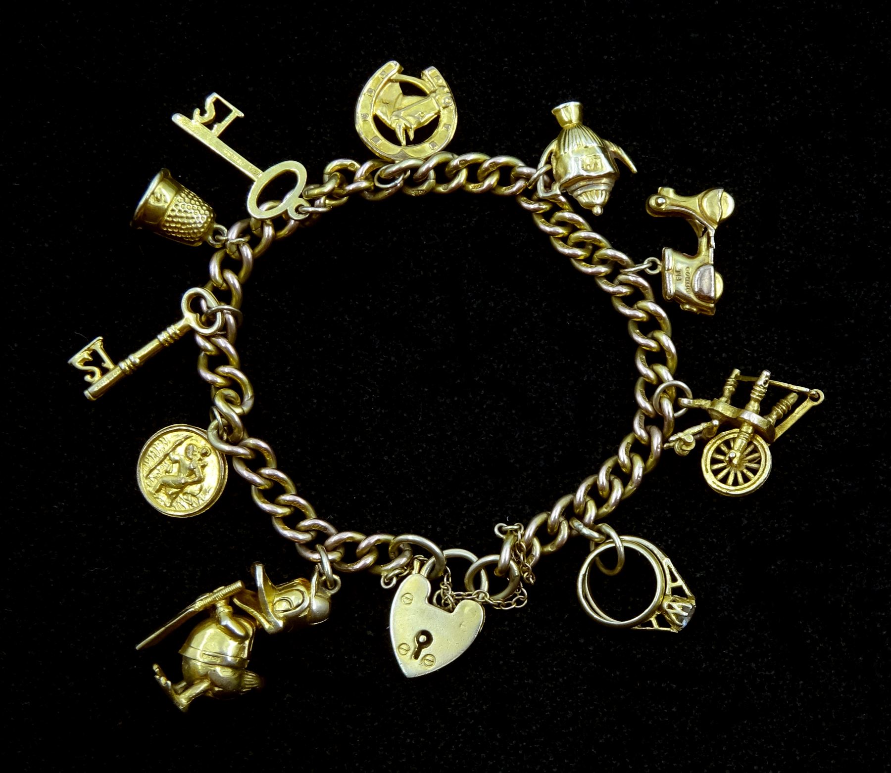 9ct gold curb chain bracelet with heart locket and ten 9ct gold charms including Donald Duck, spinning wheel, key, scooter and thimble, hallmarked or tested, approx 33.9gm