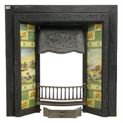 Early 20th century cast iron tiled fire surround, decorated with foliate decoration, the floral tiles surrounding central mountainous lake scene