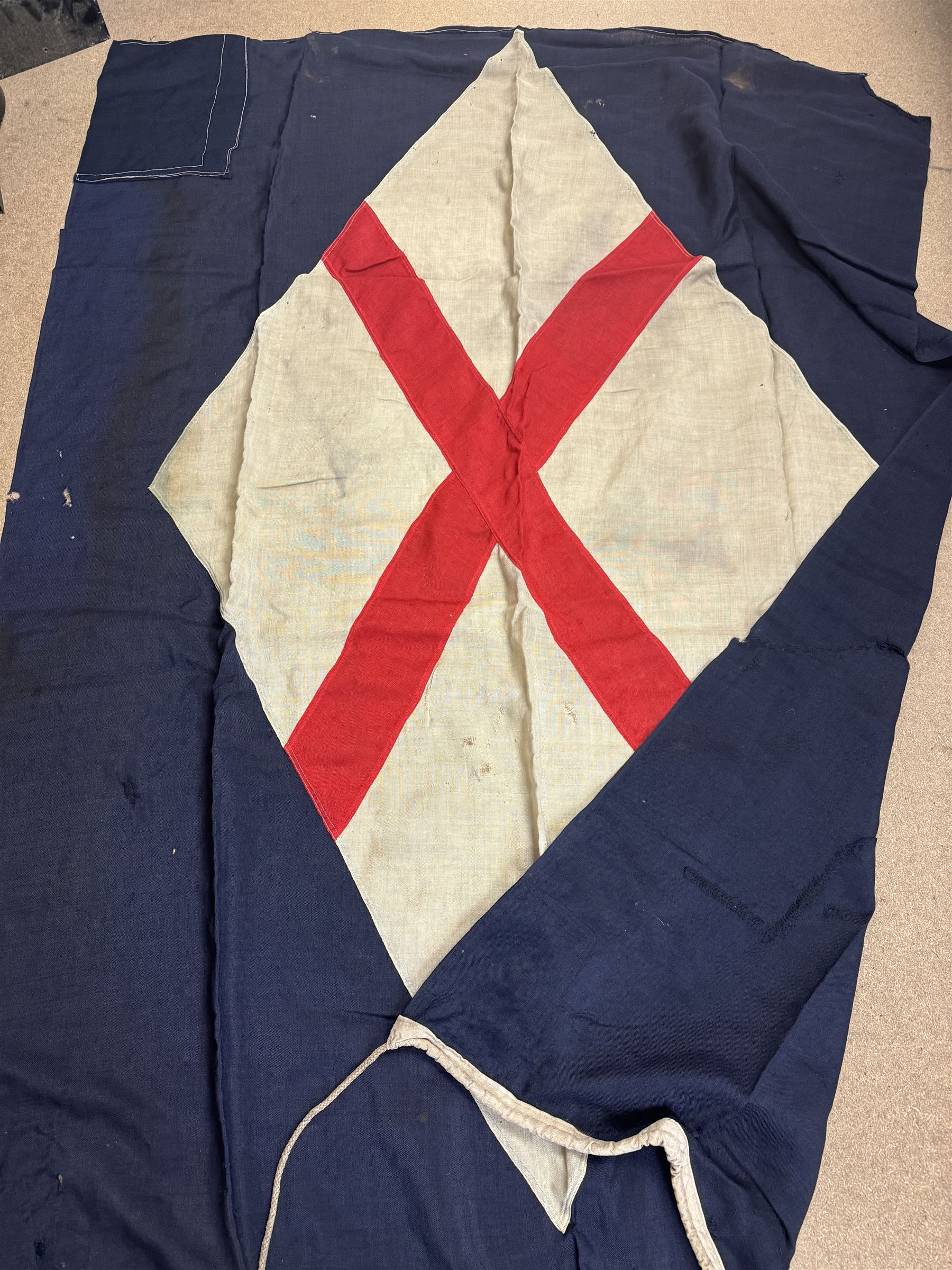 Ship's house flag, rectangular linen flag, with a white diamond and red cross to the centre, upon a cobalt blue ground, inscribed on the hoist 'Cutty Sark', H130cm, W170cm

Provenance by vendor repute: Vendor's father was a naval cadet in 1940s/50s on board HMS Worcester which was moored alongside the Cutty Sark on the River Thames at Greenhithe. He has had the flag since then. 