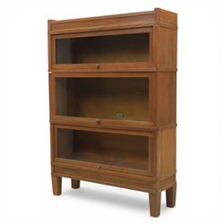 Globe Wernicke - Modular oak sectional bookcase, the three glazed up-and-over doors with panelled sides, raised on a plinth base with square supports