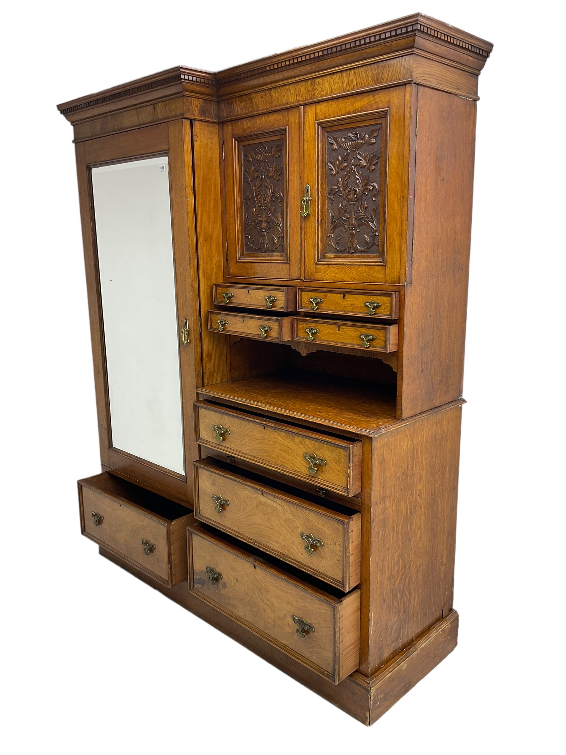 Victorian figured oak and pollard oak combination wardrobe, projecting dentil cornice, the left hand side enclosed by large bevelled mirror glazed door over drawer, the interior with sliding hanging rail, the right hand side with cupboard enclosed by two panelled doors relief carved with urn and trailed trailing foliage, four small drawers over shelf, three drawers and brushing slide, the slide with tooled and gilt blue leather inset, plinth base