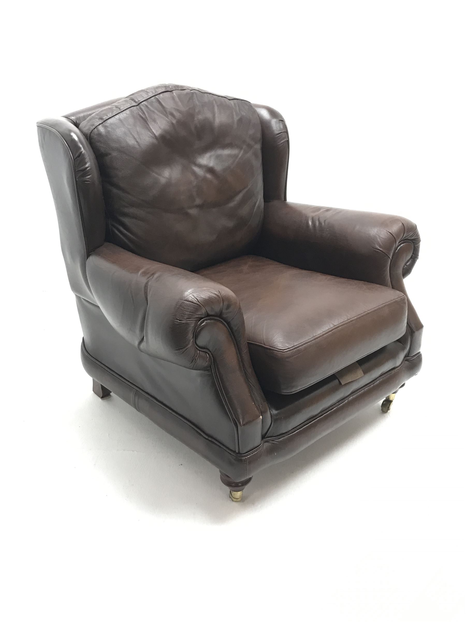 Thomas Lloyd wing back armchair upholstered in a brown leather, turned supports on castors