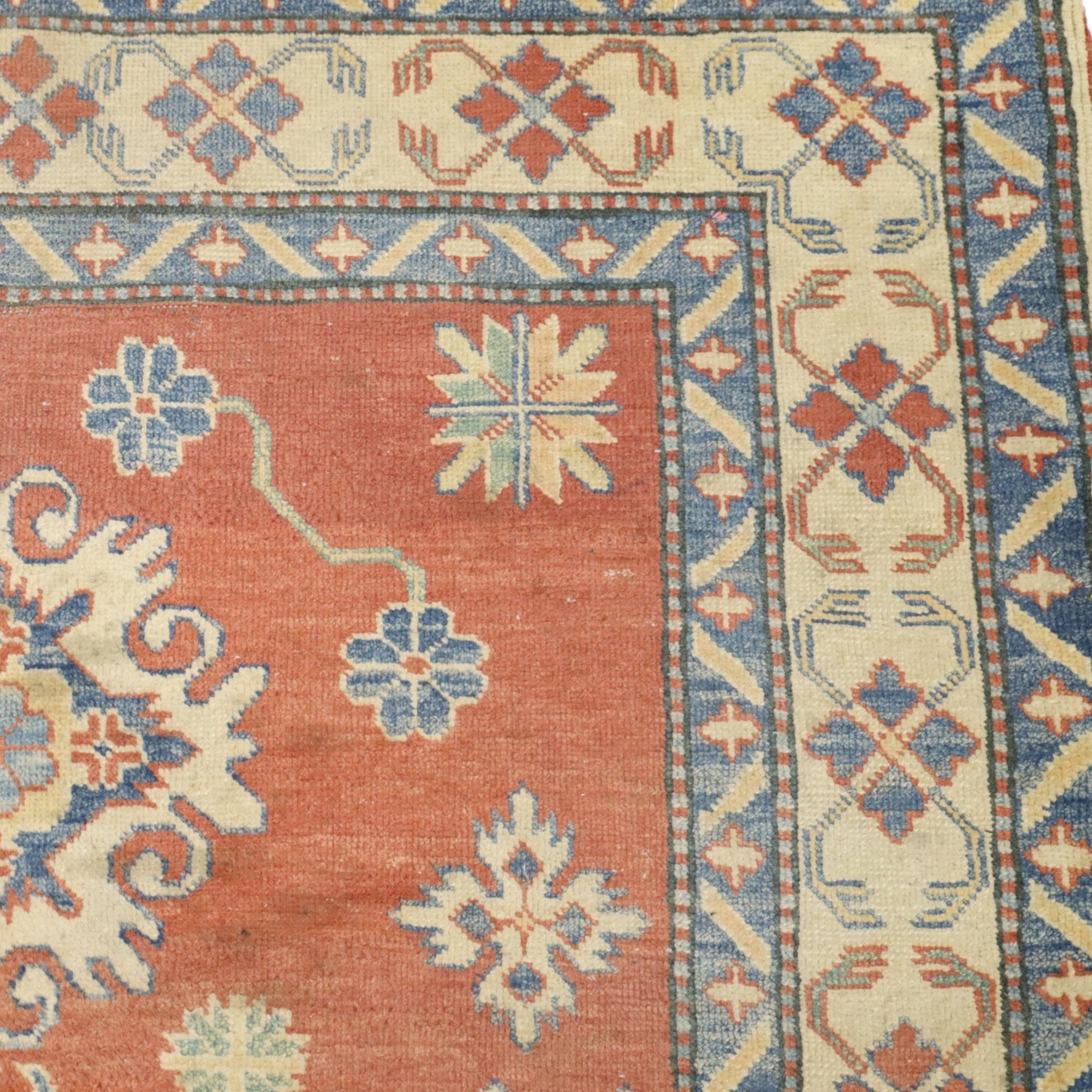 Persian Kazak vermillion ground rug, decorated with a foliate pole medallion with surrounding geometric and plant motifs, the guard bands with repeating floral and geometric design