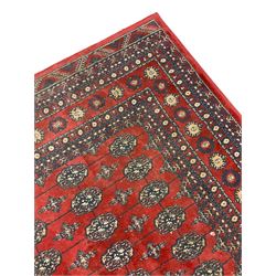 Persian Bokhara design rug, red ground and decorated with five rows of Gul motifs, geometric design border decorated with stylised motifs