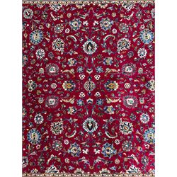 Northeastern Persian Meshed hand-knotted carpet, madder red field with an all-over design of scrolling vines, palmettes, and rosettes, within a dark blue border of palmettes and arabesques 